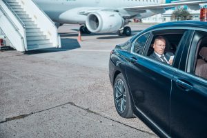 businessmanwith-smartphone-in-car-at-airport
